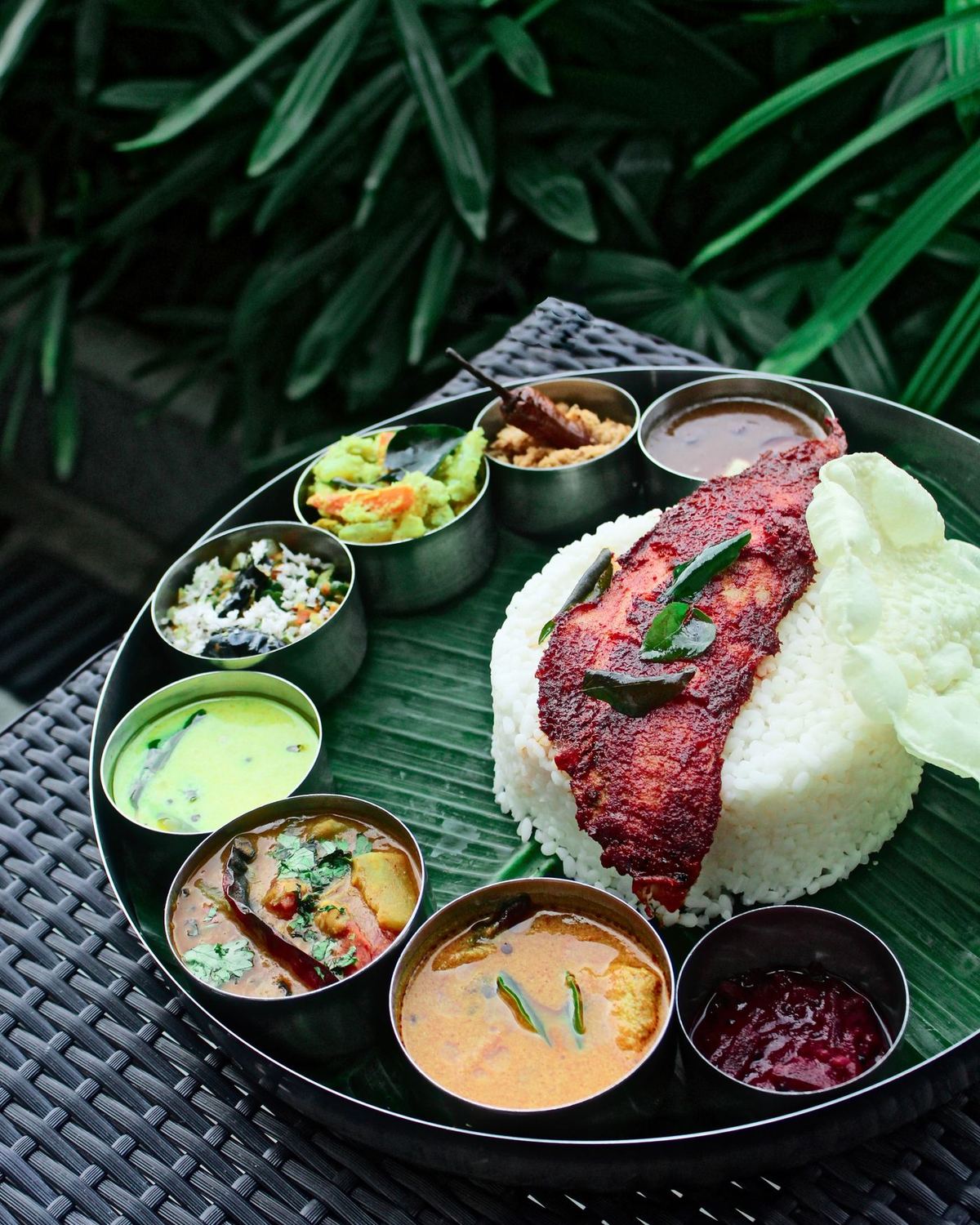 Kerala rice meal with fish fry, curries and pappadam on a banana leaf