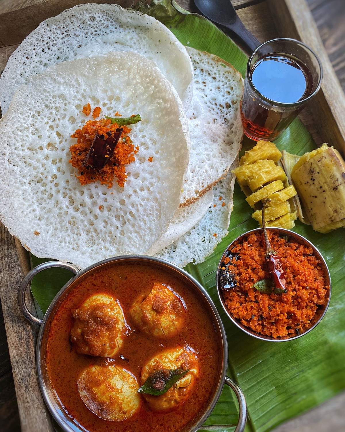 Appam with egg curry and chutney on a banana leaf